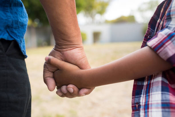 cropped image de garçon et de son grand-père tenant par la main - generation gap multi generation family vertical holding hands photos et images de collection