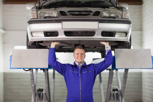 istock Smiling mechanic touching the below of a car 847984458
