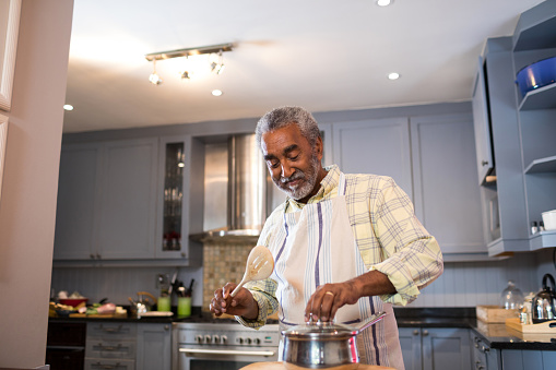 Smiling senior man preparing food in kitchen at home