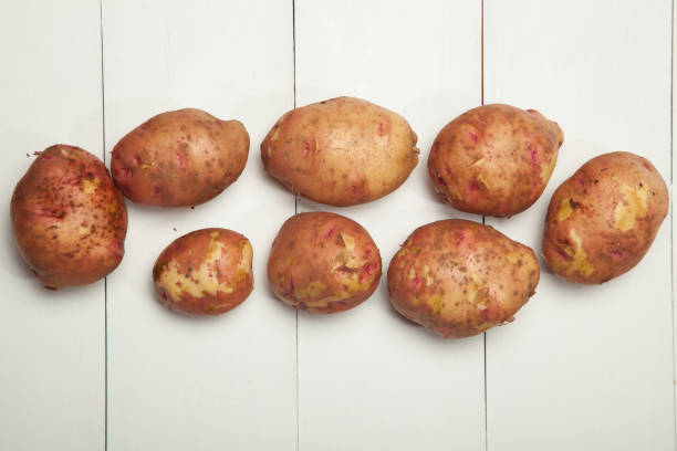 istock Potatoes on white wooden background, top view 847991684