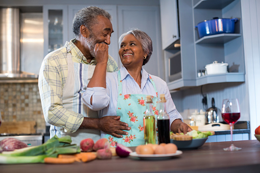 Affectionate senior couple preparing food in kitchen at home