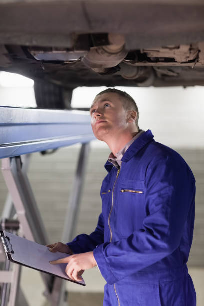 istock Mechanic looking at the below of a car 848002568