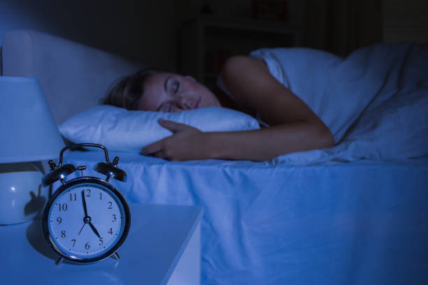 istock Focus on the alarm clock in front of sleeping woman 848020618