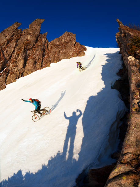 Snowmobile racers trying to turn back the overturned snow machine stuck in a snowdrift.
