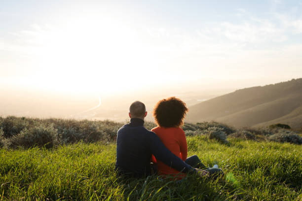 Couple sitting in a meadow and watching the sunset