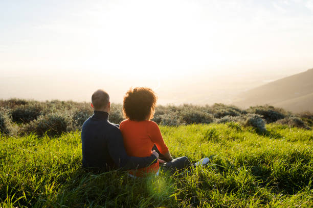 istock Couple sitting in a meadow and watching the sunset 848082652