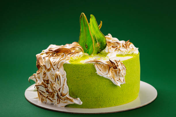 istock Birthday cake with burned meringue and colored pear slices on green background 848090720