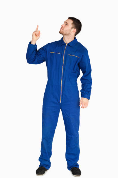 Young mechanic in boiler suit pointing up against a white background