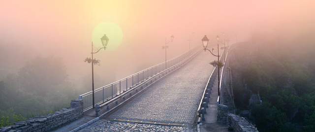 Misty morning bridge over the river below the castle in Kamyanets-Podilsky on the background of the dawn mist gentle waves give the romantic charm of the legends of Ukrainian History