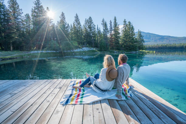 istock Young couple watching sunrise on lake pier 848131454
