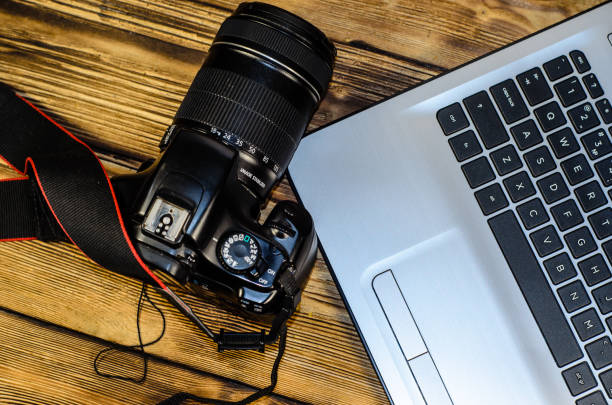 istock Modern DSLR camera and laptop on wooden table. Top view 848135898
