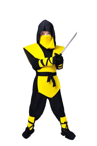 A boy in black and yellow ninja suit with a hood and mask on his face bowed his head. With a knife in one hand. Portrait in full growth. Isolated