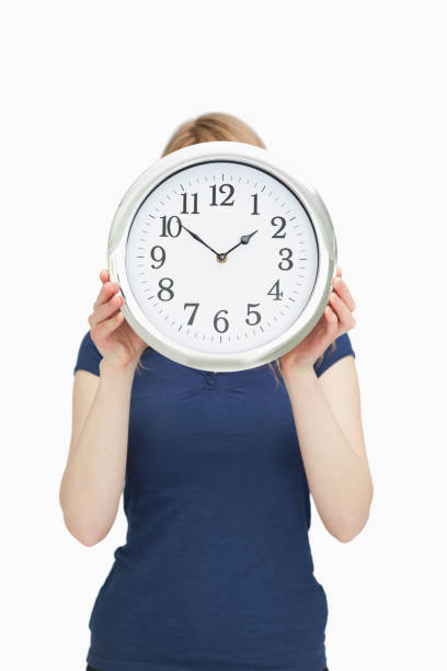 blonde woman holding a clock in front of her face - clock clock face blank isolated imagens e fotografias de stock