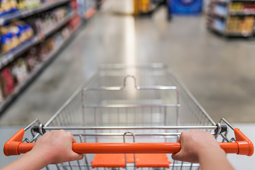 3d rendering of an empty metal shopping cart viewed from a shopper's first-person perspective, featuring red handle grips, isolated on a white background. Shopping experience.