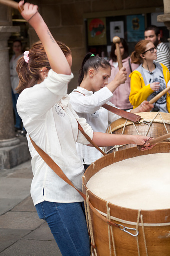Santiago de Compostela, Spain- September 9, 2017: Close-up view of young female  drummers playing in a street marching band during a parade in  Santiago de Compostela, Galicia, Spain.