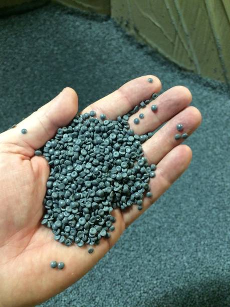 Hand holding grey post consumer recycled plastic pellets