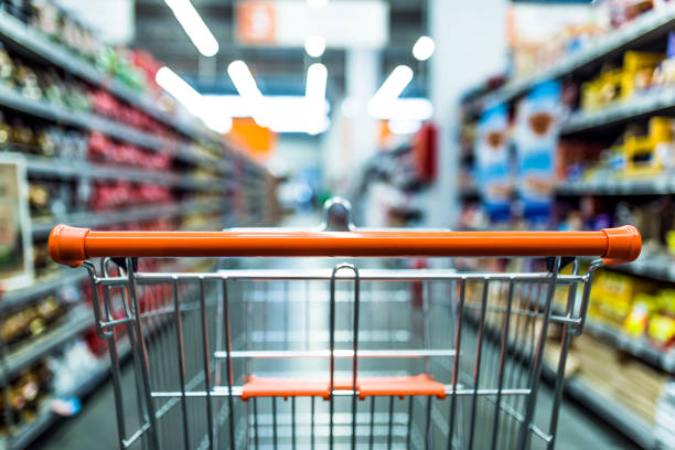 Fast shopping Abstract blurred photo of store with trolley in department store background. Supermarket aisle with empty red shopping cart cart stock pictures, royalty-free photos & images