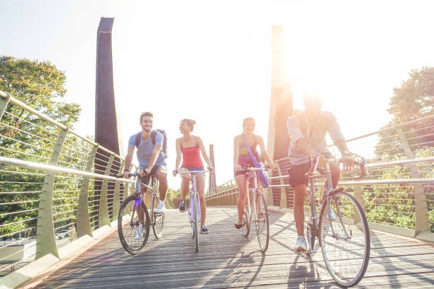 studenti felici in bicicletta d'epoca che guidano nel parco cittadino - giovani amici che si divertono insieme - giovinezza, amicizia e concetto sportivo - focus principale sul ragazzo giusto - filtro caldo con luce posteriore del sole originale - bicycle ride foto e immagini stock