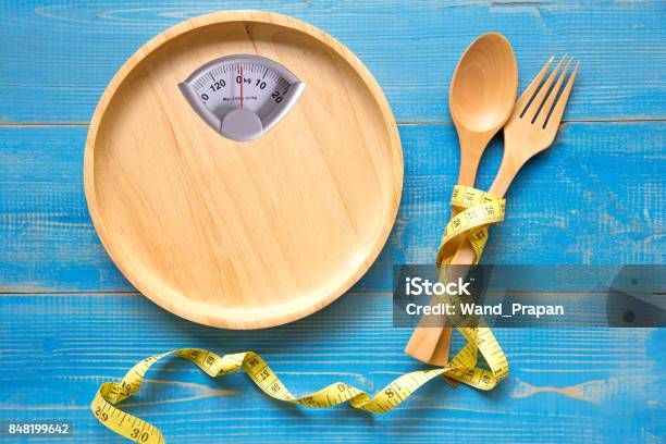 Scale Shaped On The Wood Plate With A Fork And Spoon Blue Background Diet And Healthy Concept Stock Photo - Download Image Now