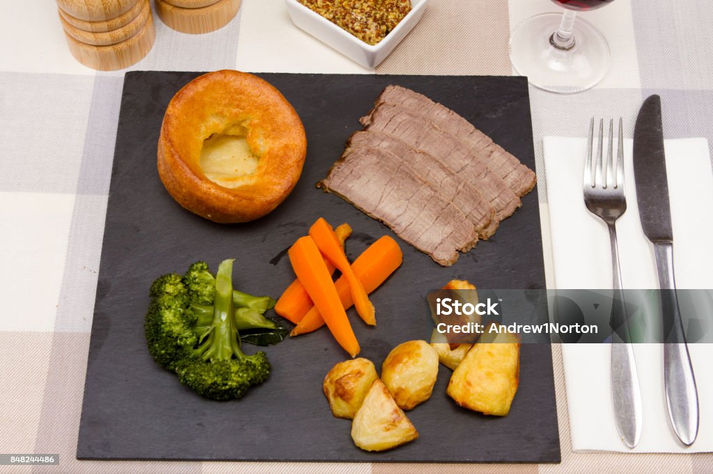 Roast topside beef A piece of cooked topside of British beef with vegetables and Yorkshire pudding Beef Stock Photo