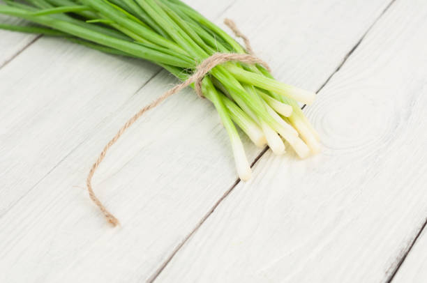 istock Tied green fresh onion on old white rustic wooden table 848277612