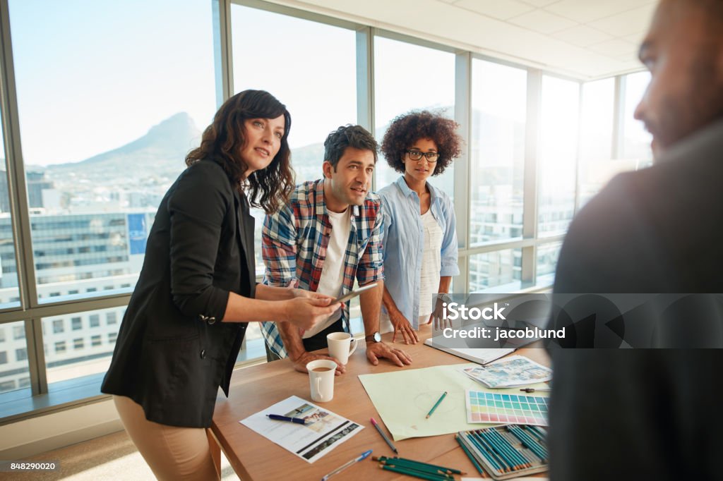 Team brainstorming over new designs in office Group of young designer working together on project. Team brainstorming over new designs in meeting  room. Travel Agency Stock Photo