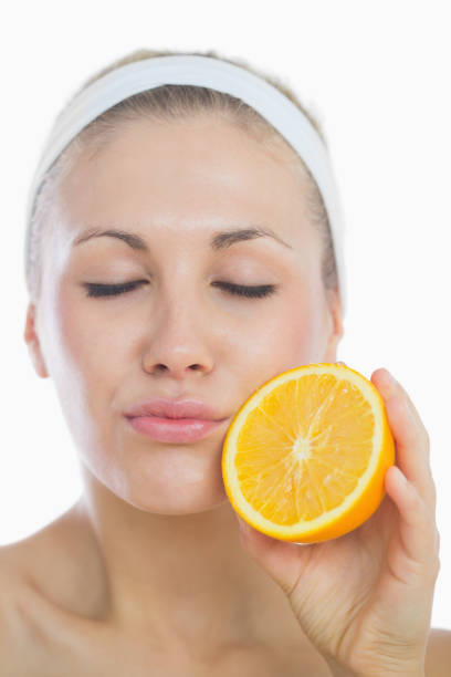 istock Young woman with eyes closed holding orange slice 848307832