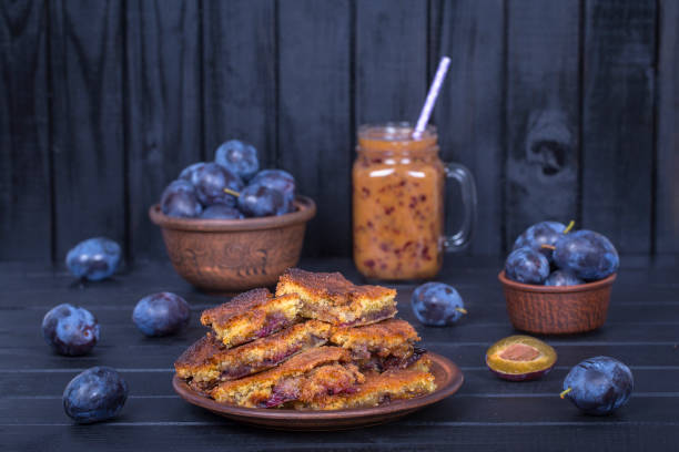 homemade plum pie in plate, plum smoothies and raw plums on black wooden background - plum fruit organic food and drink imagens e fotografias de stock