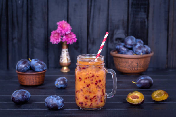 plum smoothies and raw plums on black wooden background - plum fruit organic food and drink imagens e fotografias de stock