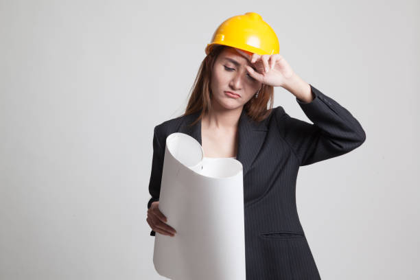 Tried Asian engineer woman with blueprints. Tried Asian engineer woman with blueprints on gray background Major Challenges for women in the construction Industry stock pictures, royalty-free photos & images