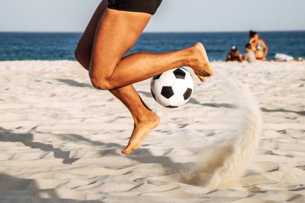 brazilian man bouncing soccer ball on beach, rio de janeiro, brazil - beach football imagens e fotografias de stock