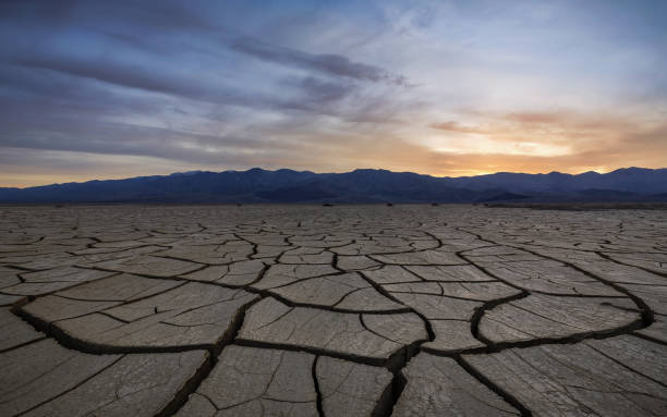 istock Sunset with clouds over a dry, cracked and scorched foreground 848401116