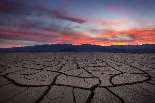 Sunlit view of cracked earth in a mud volcano landscape, showcasing natural erosion and dry textures, highlighting the rugged beauty of an arid environment.