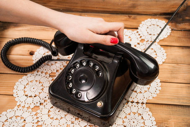 ragazza mano che tiene vecchie cuffie telefoniche su tovaglie di pizzo e sfondo in legno - landline phone women close up old fashioned foto e immagini stock