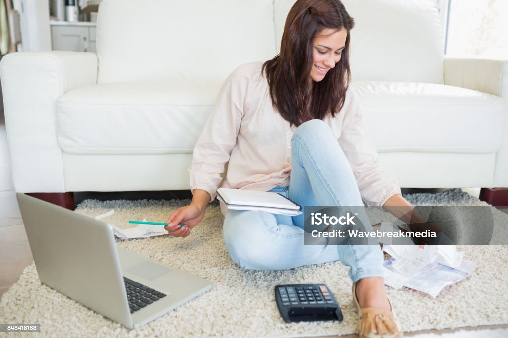 Woman using laptop to calculate bills Woman using laptop to calculate bills on floor of living room Kitchen Stock Photo