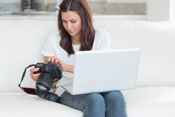 istock Woman looking at laptop while holding a camera 848442066