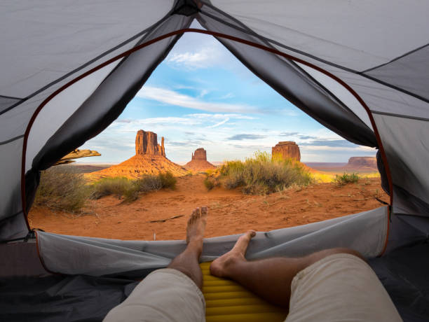 POV first person view on monument valley out of a tent POV point of view first person view from the inside of a tent with male feet and legs view over monument valley merrick butte stock pictures, royalty-free photos & images