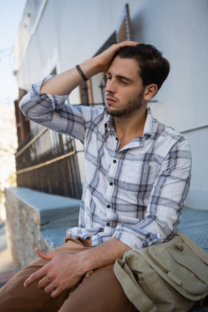istock Man with eyes closed sitting on retaining wall 848489034