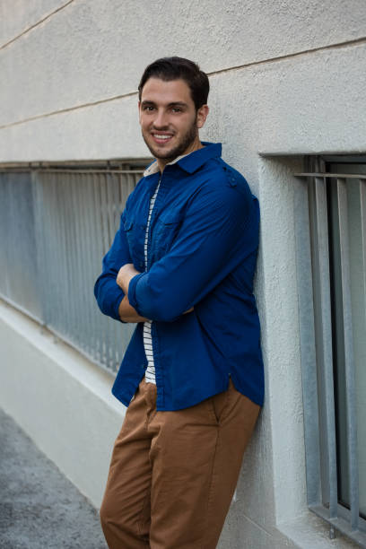 istock Confident young man with arms crossed leaning on wall 848489298