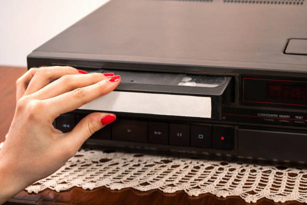 istock Woman hand inserting blank VHS cassette in old video recorder 848502416