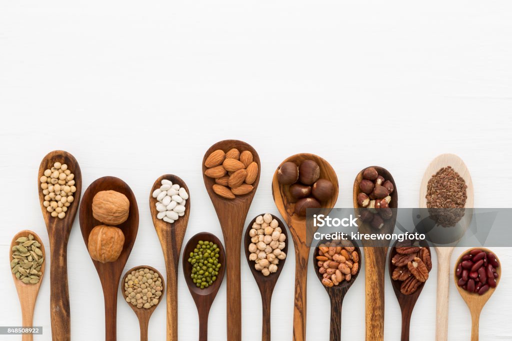 Different kind of beans and lentils in wooden spoon on white wood background. mung bean, groundnut, walnuts, macadamia, almond, soybean, red kidney bean, black bean, sesame, corn, red bean and brown pinto beans Seed Stock Photo