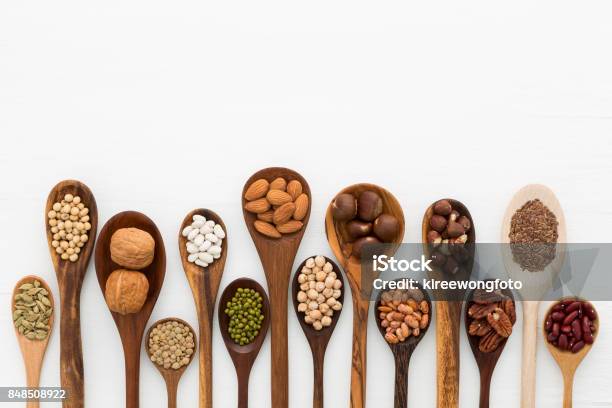 Different Kind Of Beans And Lentils In Wooden Spoon On White Wood Background Mung Bean Groundnut Walnuts Macadamia Almond Soybean Red Kidney Bean Black Bean Sesame Corn Red Bean And Brown Pinto Beans Stock Photo - Download Image Now