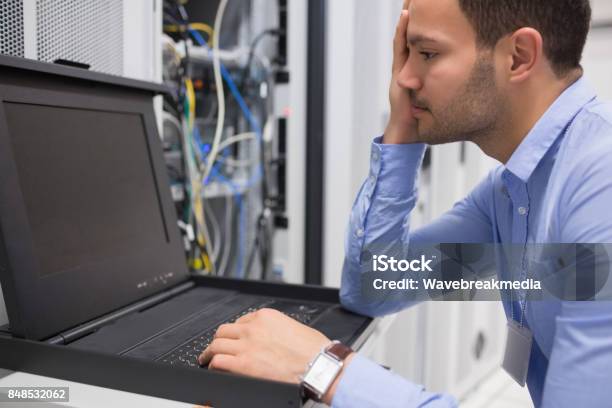 Man Running Diagnostics Of Servers Stock Photo - Download Image Now - 20-24 Years, 20-29 Years, Adjusting