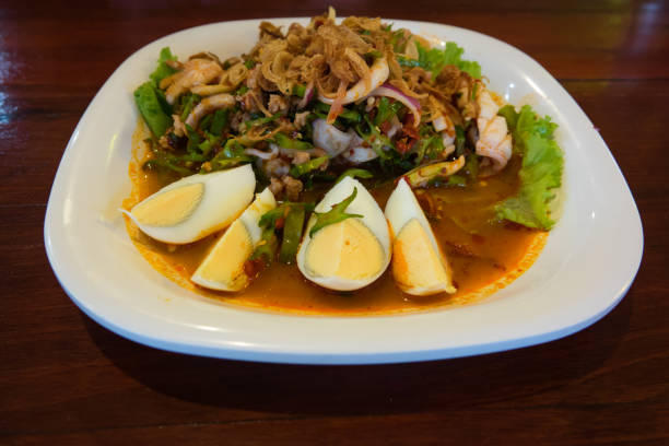 top view Wing Bean Shrimp Salad with Fresh shrimp and squid and boiled egg on white plate on wooden table