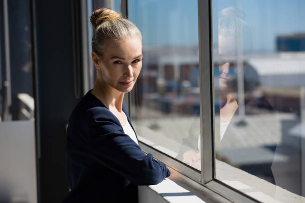 istock Confident woman standing by window in office 848538500