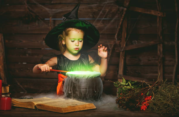 хеллоуин. маленькая ведьма ребенка приготовления зелья в котле с заклинанием книги - 6728 стоковые фото и изображения