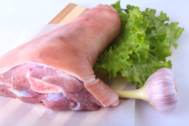 istock Raw pork knuckle, garlic and lettuce leaves on a cutting board. Selective focus. Ready for cooking. 848550214