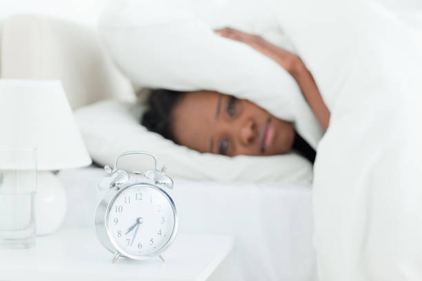 istock Young woman covering her ears while her alarm clock is ringing 848557428