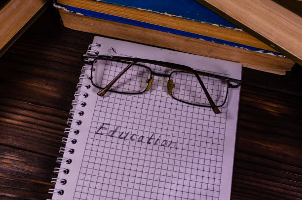 istock Notepad and eyeglasses in front of books. Education inscription 848580976