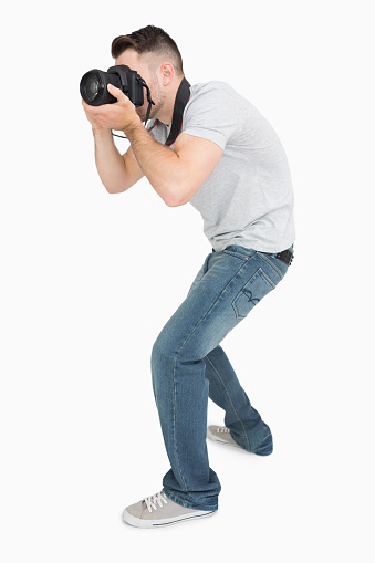 Young male photographer with photographic camera over white background